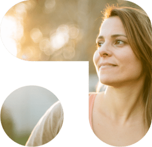 Kvinne smiler utendørs i sollys, med lyse omgivelser som fremhever hennes ansikt.